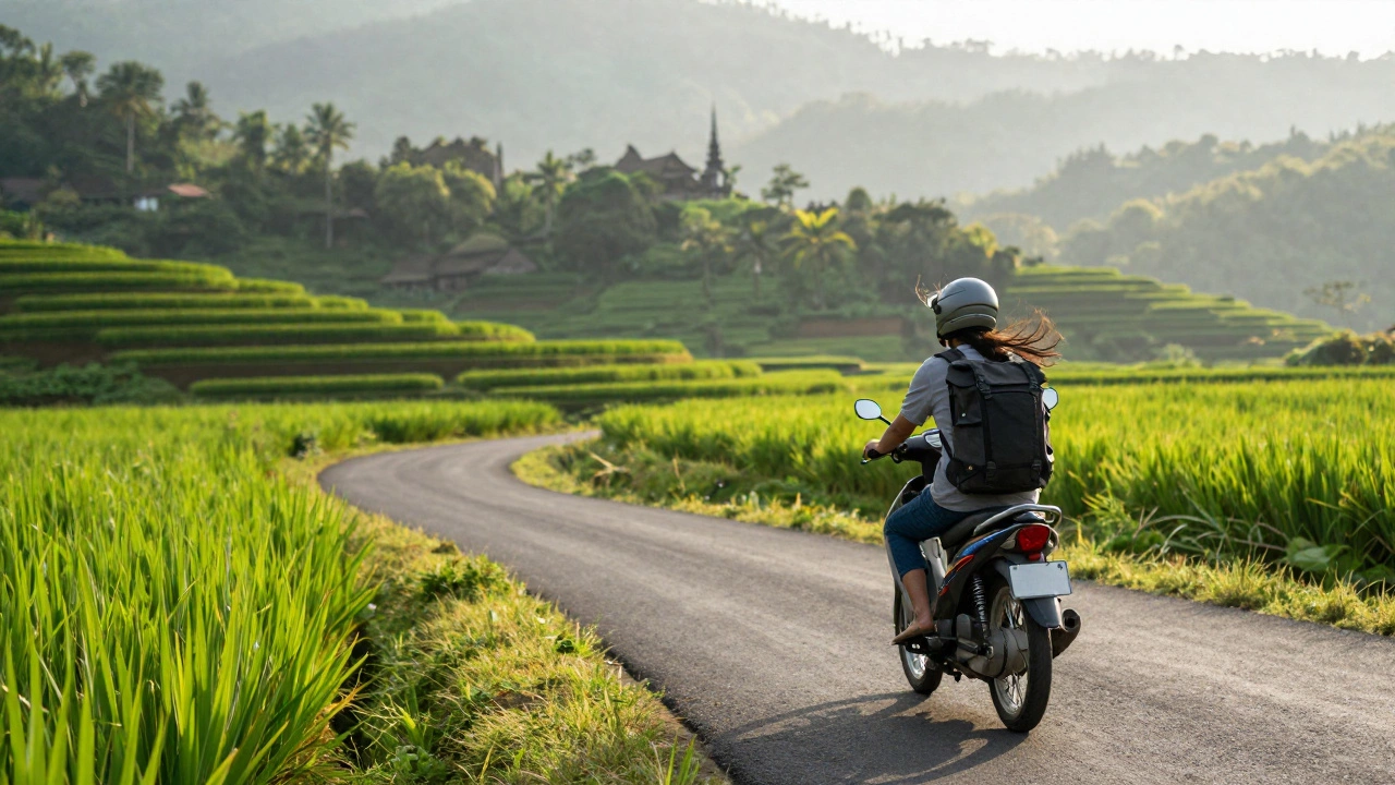 Турист на мотоцикле едет по зелёным рисовым террасам Бали на фоне туманных холмов.
